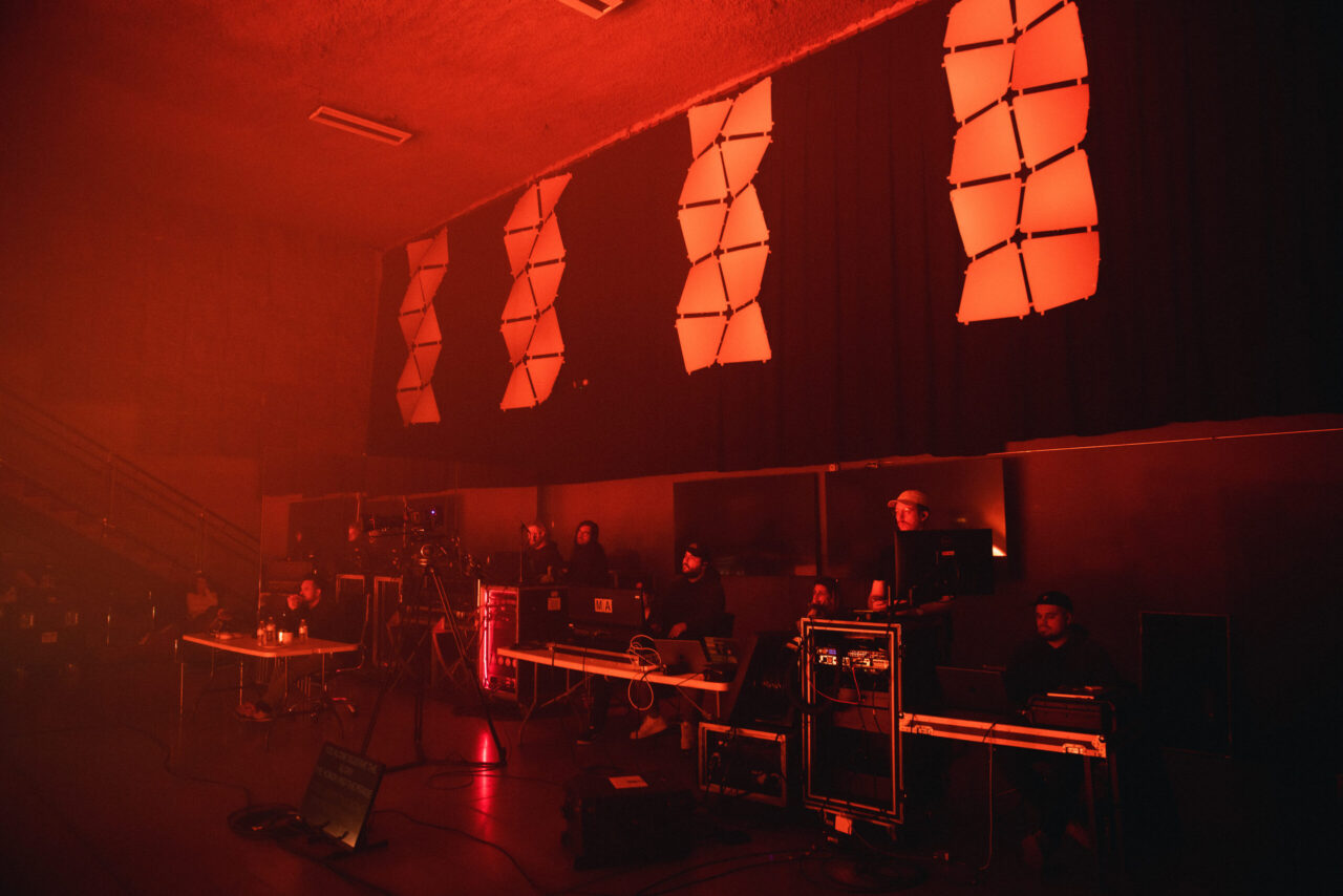 Red-lit control room packed with people, cables, and gear—shows the real behind-the-scenes hustle on a shoestring setup.